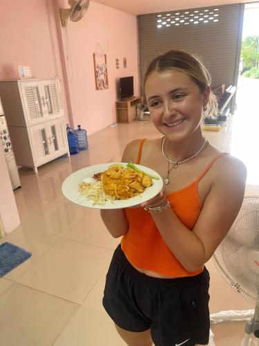 a woman is holding a plate of food at Connexion in Ko Yao Noi