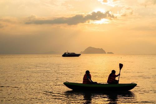 two people in a boat in the water with a ship at Connexion in Ko Yao Noi