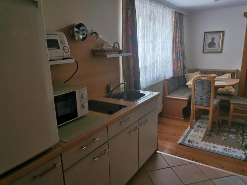 une cuisine avec un évier et un micro-ondes dans l'établissement Haus am Bach, à Kirchberg in Tirol