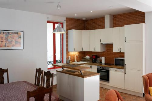 une cuisine avec des armoires blanches et une table à l'intérieur dans l'établissement La Maison Rouge, à Saint-Sauveur-en-Puisaye