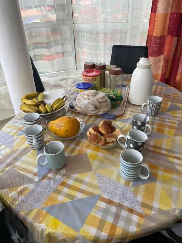 una mesa con un plato de comida y tazas. en Maison Residencial casa de ferias en Pedra Badejo