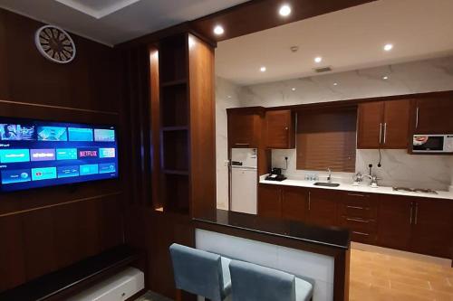 a kitchen with wooden cabinets and a tv on the wall at شقق نيروز ان للوحدات المخدومة in Jeddah