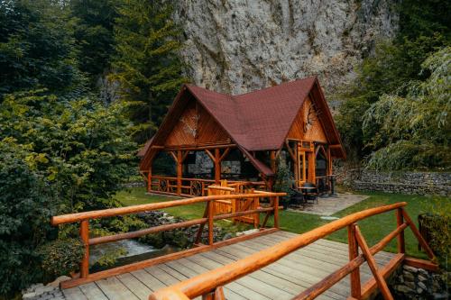 a wooden pavilion with a wooden bridge in a forest at Casa Cheile Dâmbovicioarei - Cabana 1 in Dîmbovicioara