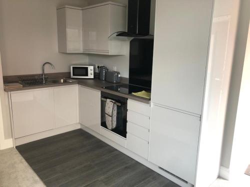 a white kitchen with a sink and a microwave at New ground floor 2 bed flat close to the beach in Southbourne