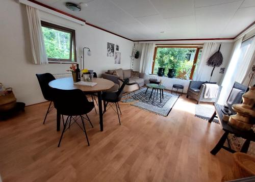 sala de estar con mesa, sillas y sofá en Heerlijk chalet in prachtige natuur., en Doornspijk