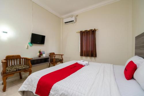 a bedroom with a bed and a chair and a television at RedDoorz @ Pematangsiantar in Pematangsiantar