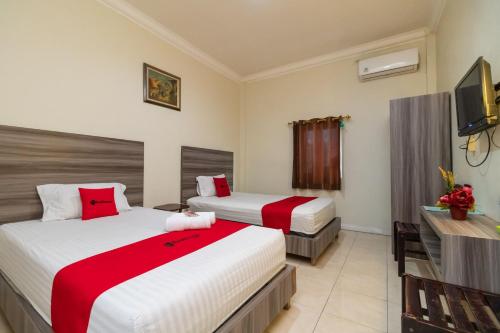 a hotel room with two beds and a television at RedDoorz @ Pematangsiantar in Pematangsiantar