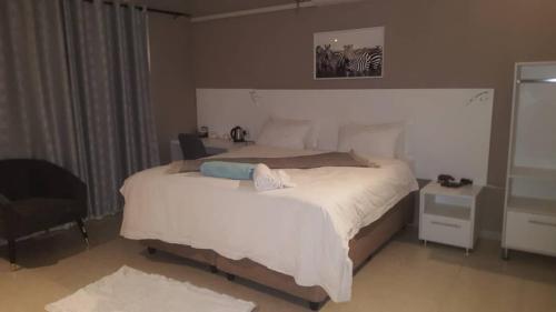 a bedroom with a large white bed and a chair at LEGENDS EXECUTIVE LODGE in Choma