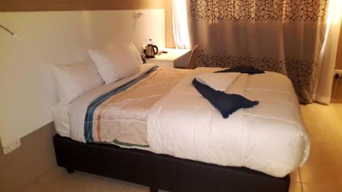 a bedroom with a bed with white sheets and pillows at LEGENDS EXECUTIVE LODGE in Choma