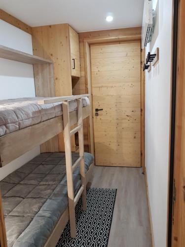 een kleine kamer met 2 stapelbedden en een deur bij Courchevel 1550 - SUPERBE appartement SKIS AUX PIEDS ! in Courchevel