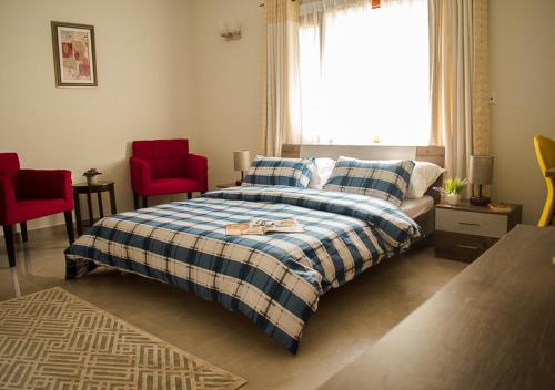 a bedroom with a bed and two red chairs at Hype Holiday Homes in Karachi