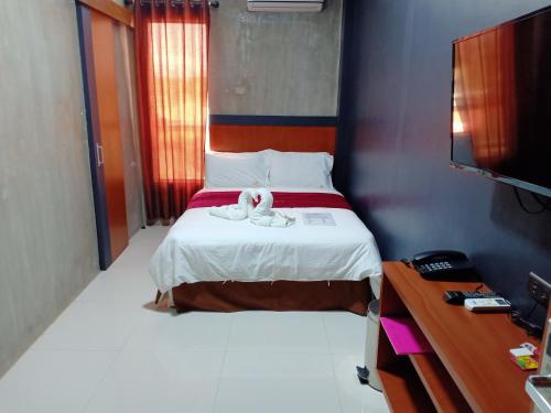 a bedroom with a bed with two white towels on it at La Gensol Plaza Hotel in Mamburao