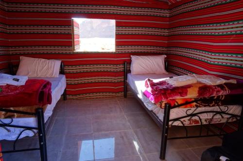 two beds in a room with a striped wall at Desert Guide Tour in Wadi Rum