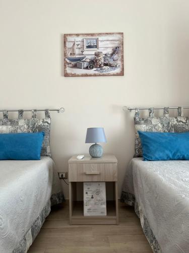 a bedroom with two beds and a night stand with a lamp at La Casa di Zia Ninì in Villaggio Pirandello