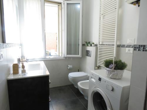 a bathroom with a toilet and a sink and a washing machine at Pasubio Apartment in Bologna