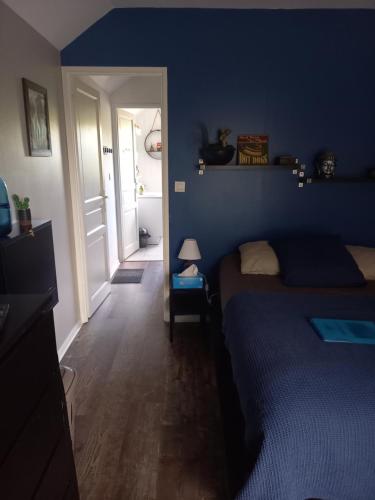 - une chambre avec un lit et un mur bleu dans l'établissement CHRISMARIE, à Bois-Guillaume