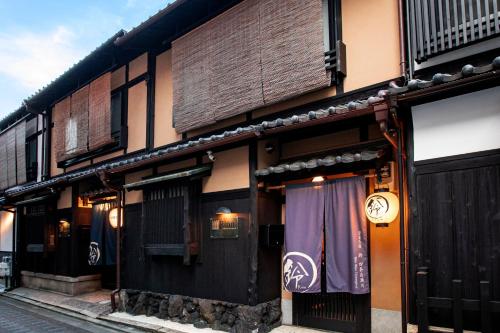 een gebouw met zwarte deuren en ramen in een straat bij Rinn Shijo Takasegawa in Kyoto