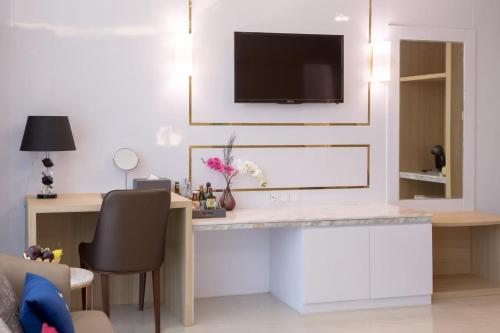 a living room with a desk with a tv on a wall at Elegant Airport Hotel in Bangkok