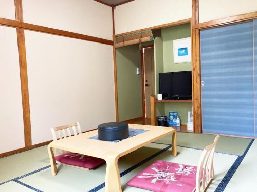een kamer met een tafel en stoelen en een televisie bij Shinyu Onsen Kurikomaso in Kurihara