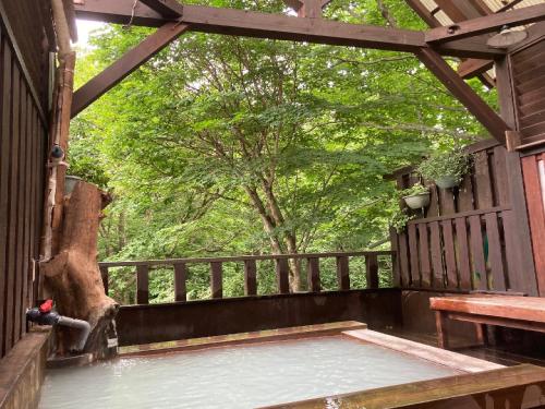 a screened in porch with a bench and a tree at Shinyu Onsen Kurikomaso in Kurihara