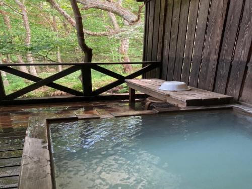 een zwembad met een bank op een veranda bij Shinyu Onsen Kurikomaso in Kurihara