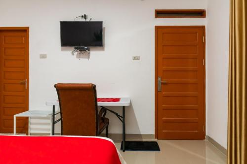 a room with a desk and a tv on a wall at RedDoorz @ Aldos Villa Silangit in Siborongborong