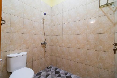 a bathroom with a toilet and a tiled wall at RedDoorz @ Aldos Villa Silangit in Siborongborong