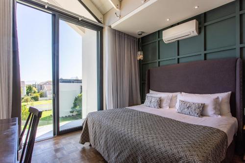 a bedroom with a bed and a large window at Polo Village 8 Val de Vie Estate in Paarl