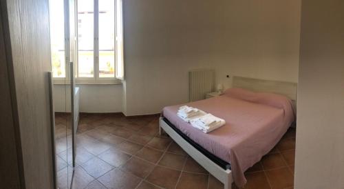 una camera da letto con un letto con lenzuola rosa e una finestra di A casa di Noemi a L'Aquila