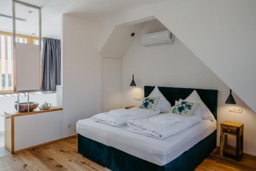 a bedroom with a bed with white sheets and blue pillows at Weinberg Chalet 2 in Eisenberg an der Pinka