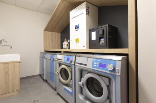 a laundry room with three washing machines and a sink at Résidence Club MMV Samoens in Samoëns