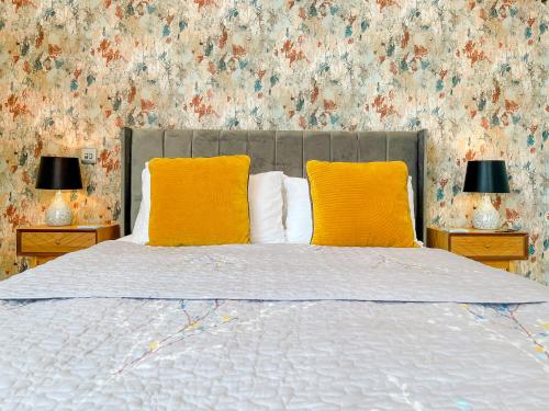 a bed with two yellow pillows and two lamps at Ashfield Boutique Stays in Altrincham