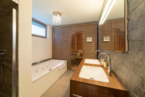 een badkamer met een groot bad, een wastafel en een bad bij Primula in Wildhaus