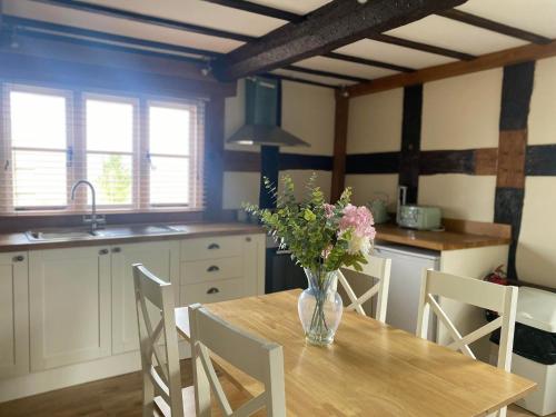a kitchen with a table with a vase of flowers on it at Alexander Park B&B in Ledbury