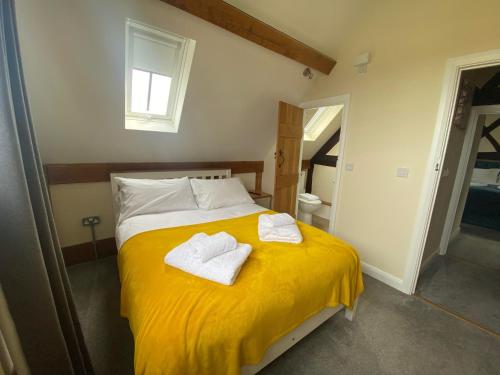 a bedroom with a yellow bed with towels on it at Alexander Park B&B in Ledbury