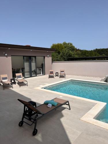 a swimming pool with chairs and a table next to it at Villa Vida, Medulin - Bazen i jacuzzi in Medulin