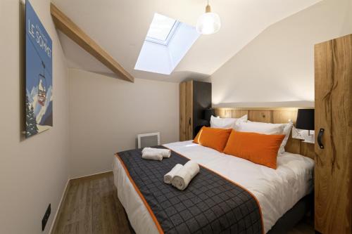 a bedroom with a bed with orange pillows and a window at Résidence Club MMV Samoens in Samoëns