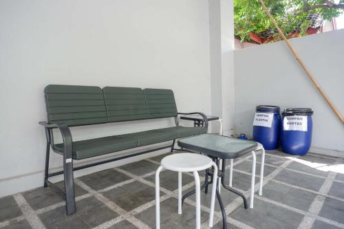 a green bench and stool next to two trash cans at RedDoorz Syariah near Gerbang Tol Krapyak 2 Semarang in Kalibanteng-kidul