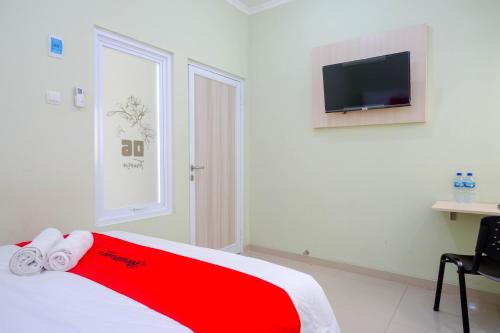 a bedroom with a red and white bed and a tv at RedDoorz Syariah near Gerbang Tol Krapyak 2 Semarang in Kalibanteng-kidul