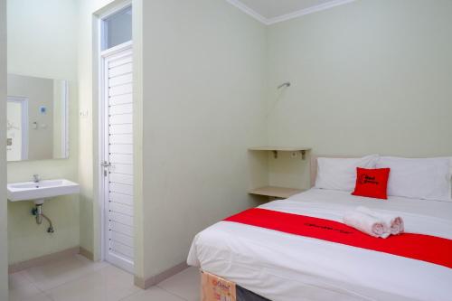 - une chambre avec un grand lit blanc et un oreiller rouge dans l'établissement RedDoorz Syariah near Gerbang Tol Krapyak 2 Semarang, à Kalibanteng-kidul