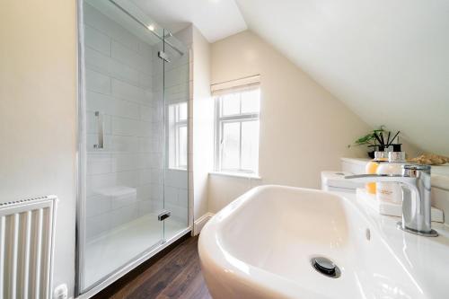 a white bathroom with a shower and a sink at Robins Nest Cottage in Blairgowrie