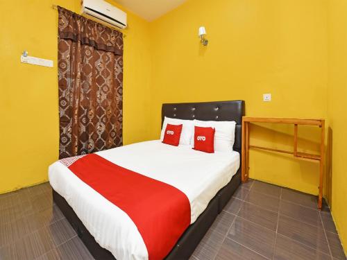 a bedroom with a large bed with red pillows at OYO 90561 Awan Biru Motel in Pantai Cenang
