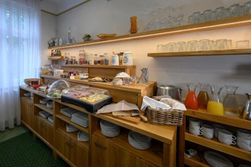 a kitchen with wooden shelves with food and dishes at Hotel Zelená Marina in Vrchlabí
