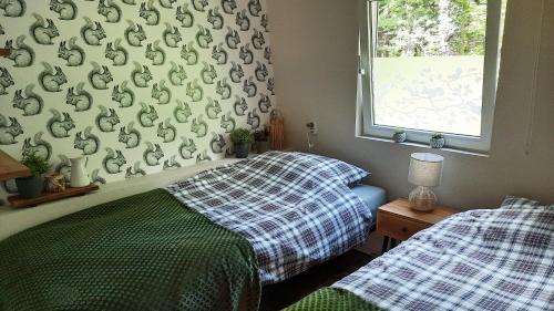 2 camas individuais num quarto com papel de parede verde e branco em Sfeervol boshuisje in natuurgebied em Steenbergen