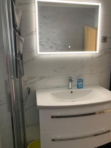 La salle de bains est pourvue d'un lavabo blanc et d'un miroir. dans l'établissement Apartman Magica, à Grebaštica