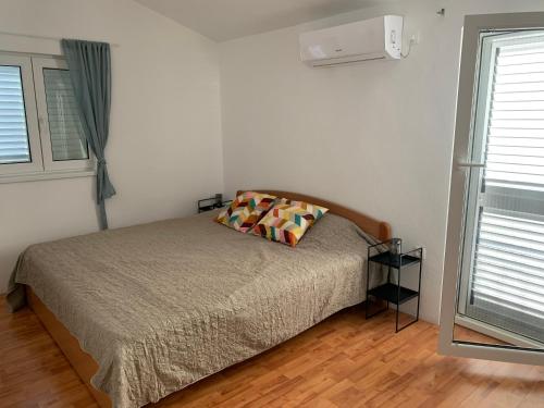 een slaapkamer met een bed met 2 kussens erop bij Apartman Magica in Grebaštica