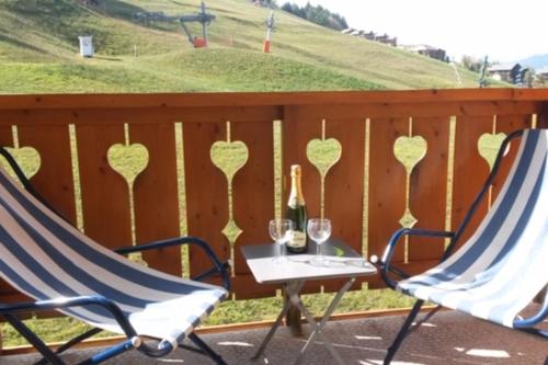 two chairs and a table with wine glasses on a fence at Le Chalet de Montalbert 25C in Montalbert