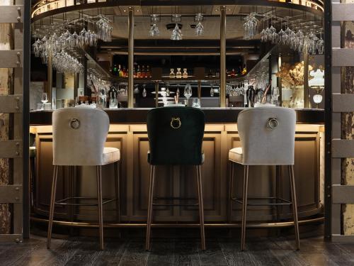 two bar stools at a bar with glasses at The Porter House Hotel Sydney - MGallery in Sydney