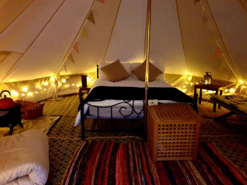 ein Schlafzimmer mit einem Bett in einem Zelt mit Beleuchtung in der Unterkunft Luxury 5m bell tent with log burner near Whitby in Saltburn-by-the-Sea