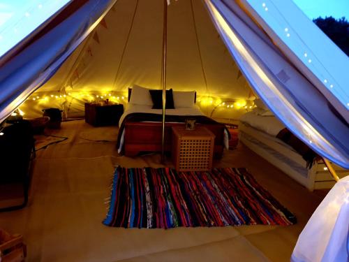 a tent with a bed and a rug in a room at 6m bell tent with log burner located near Whitby in Liverton